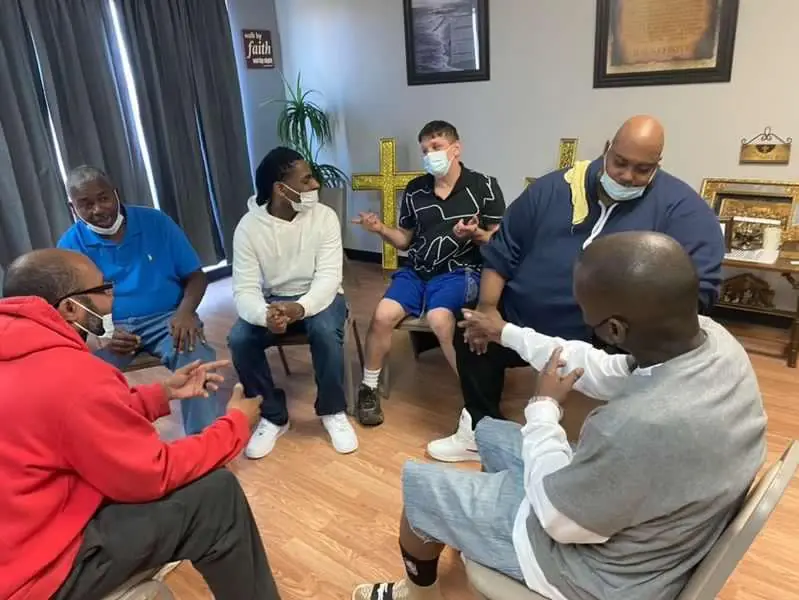 Men seated in a circle during a Trinity Community Coalition Outreach group support session